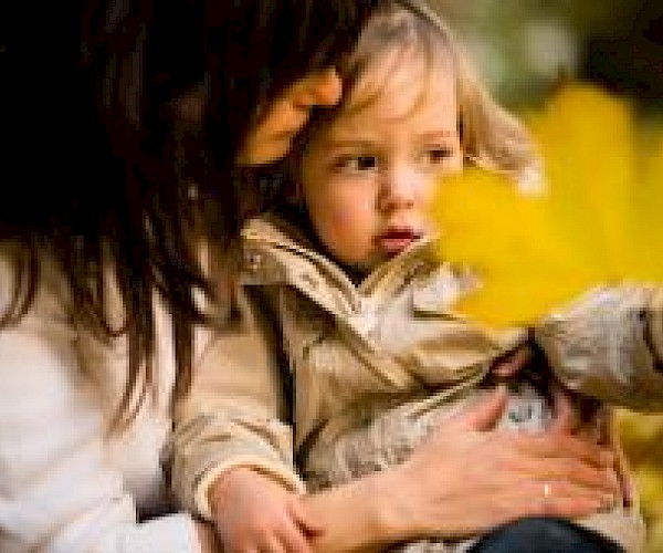 Young girl sitting on a woman's lap outside