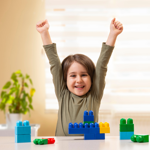 Young girl with arms up in the air in front of bricks