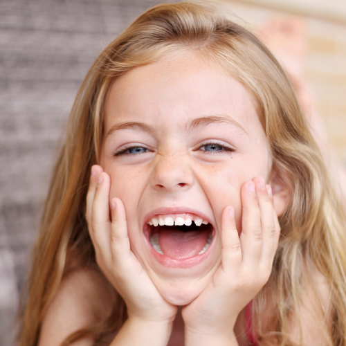 Happy, smiling young girl cupping face in her hands