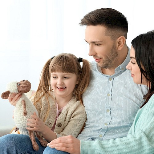 Family group of a man, woman and young girl sitting together and smiling