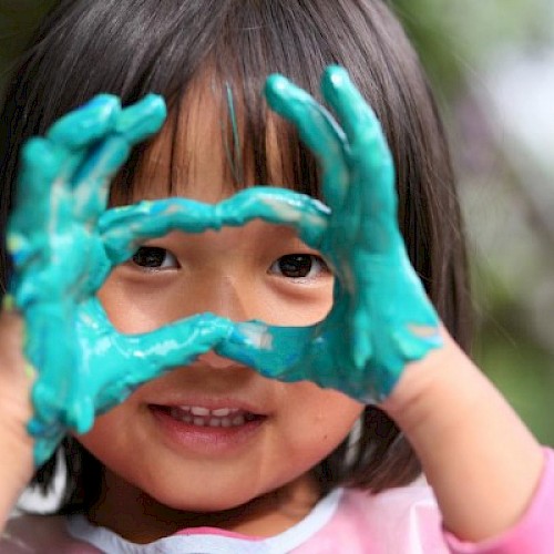 Minority Ethinc young girl making a heart with her blue paint covered hands